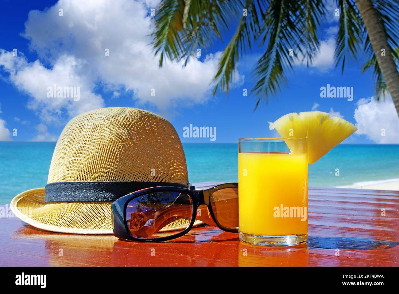 Sonnenhut mit Sonnenbrille und Fruchtsaft unter Palmen am Strand in ...