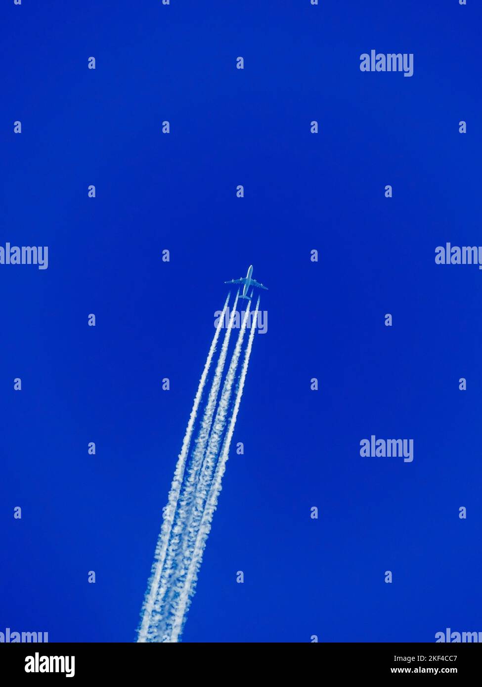 Ein Flugzeug mit Kondensstreifen am blauen Himmel. Flugreise in den Urlaub, Fernweh, Urlaub, Reisen, Stock Photo
