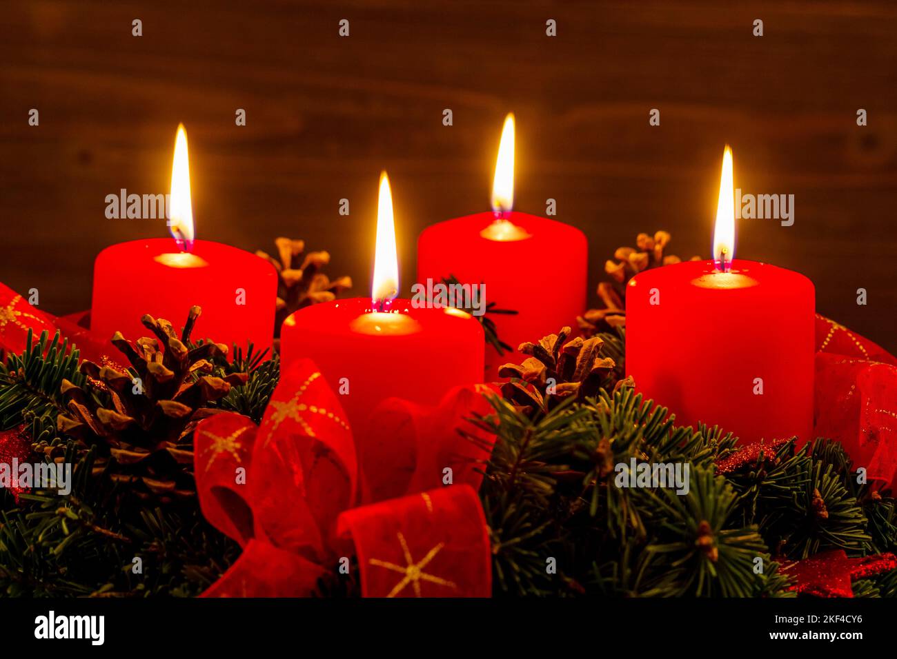 Ein Adventskranz mit vier brennenden Kerzen sorgt für eine romantische Stimmung zum Advent, 4 brennende Kerzen, 4. Advent, Weihnachten, Heilig Abend, Stock Photo