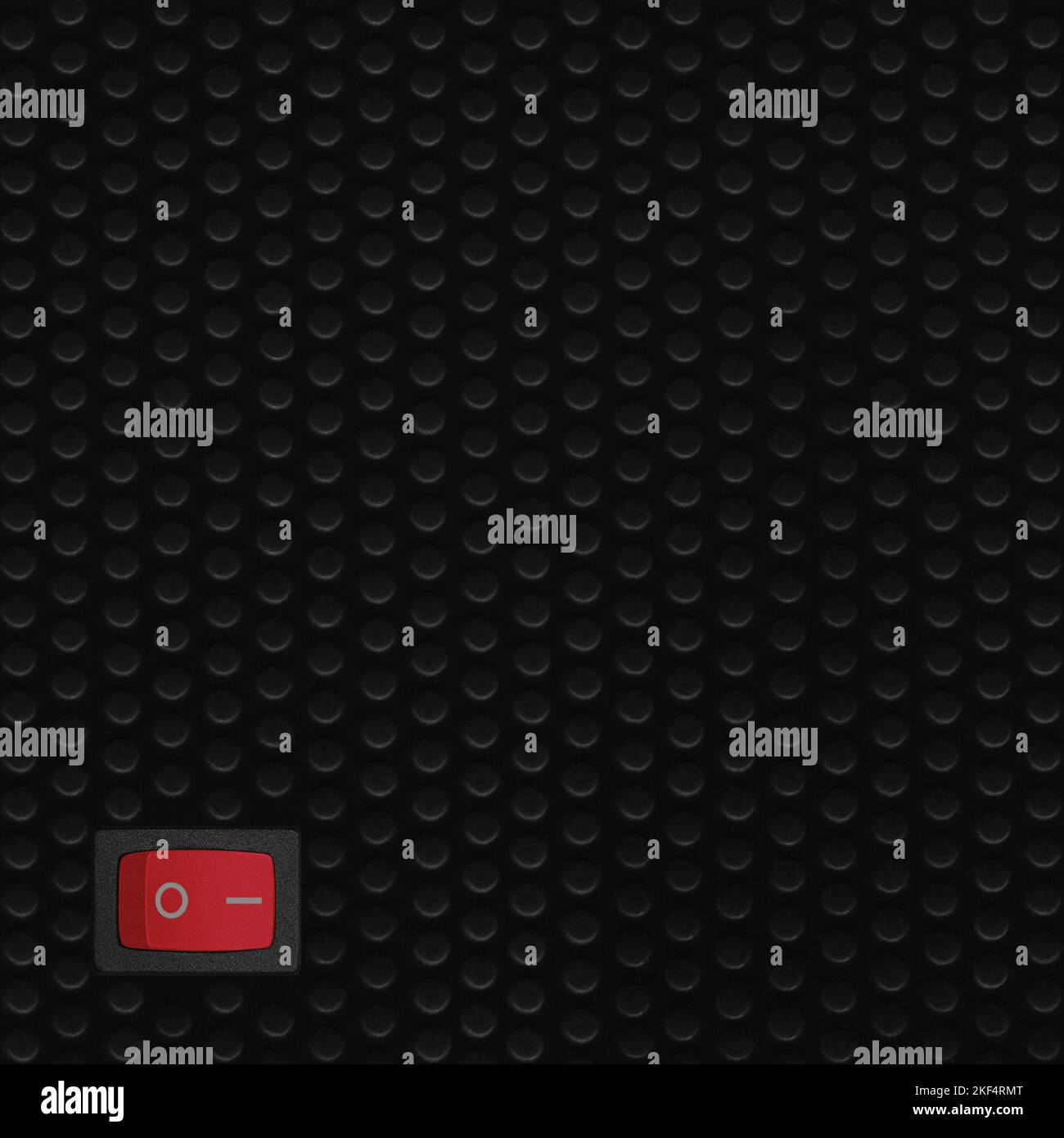 Red rectangle rocker power switch in on position, black abstract dot texture frame vertical pattern, natural blank empty copy space background Stock Photo