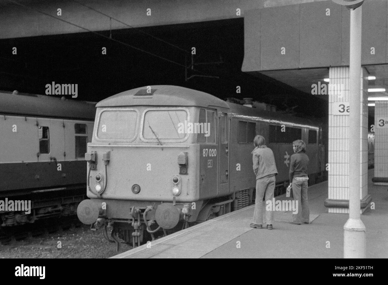 original british rail electric locomotive class 87 number 87020 on passenger service being examined by two young trainspotters birmingham new street station late 1970s early 1980s Stock Photo