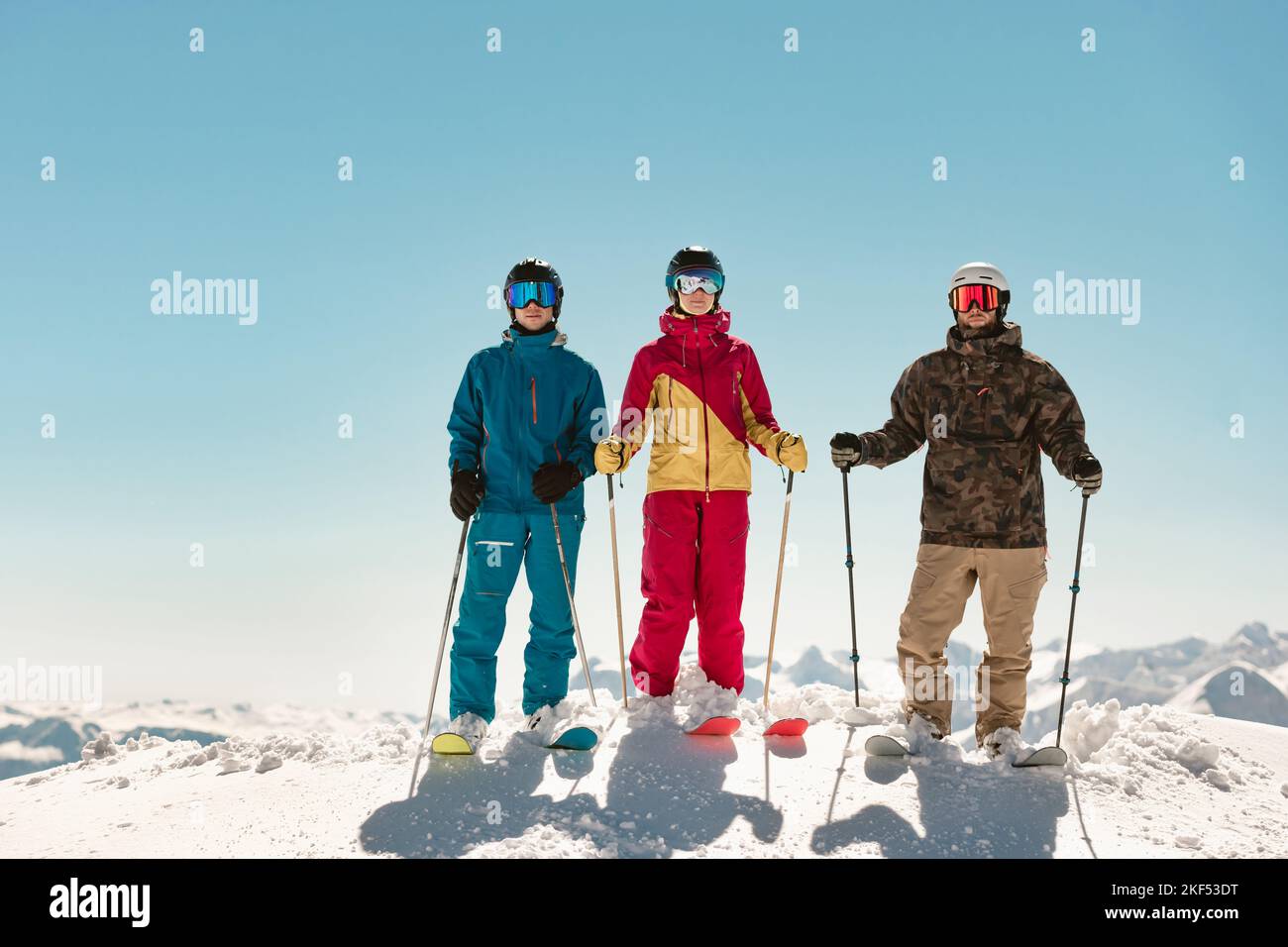 Three young skiers are standing at mountain top Stock Photo
