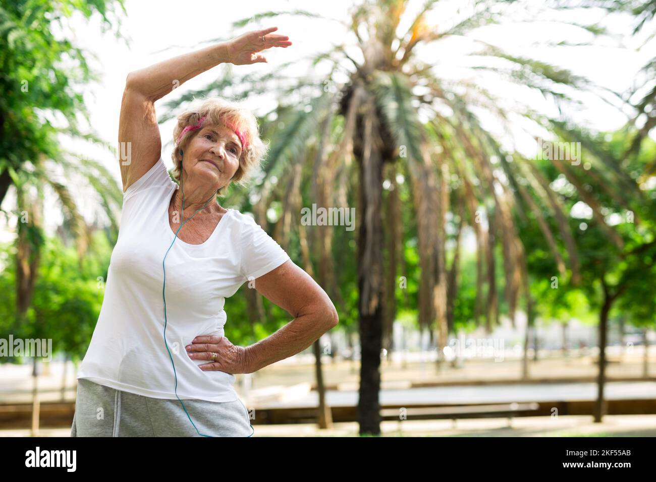 Aged woman warming up in park Stock Photo