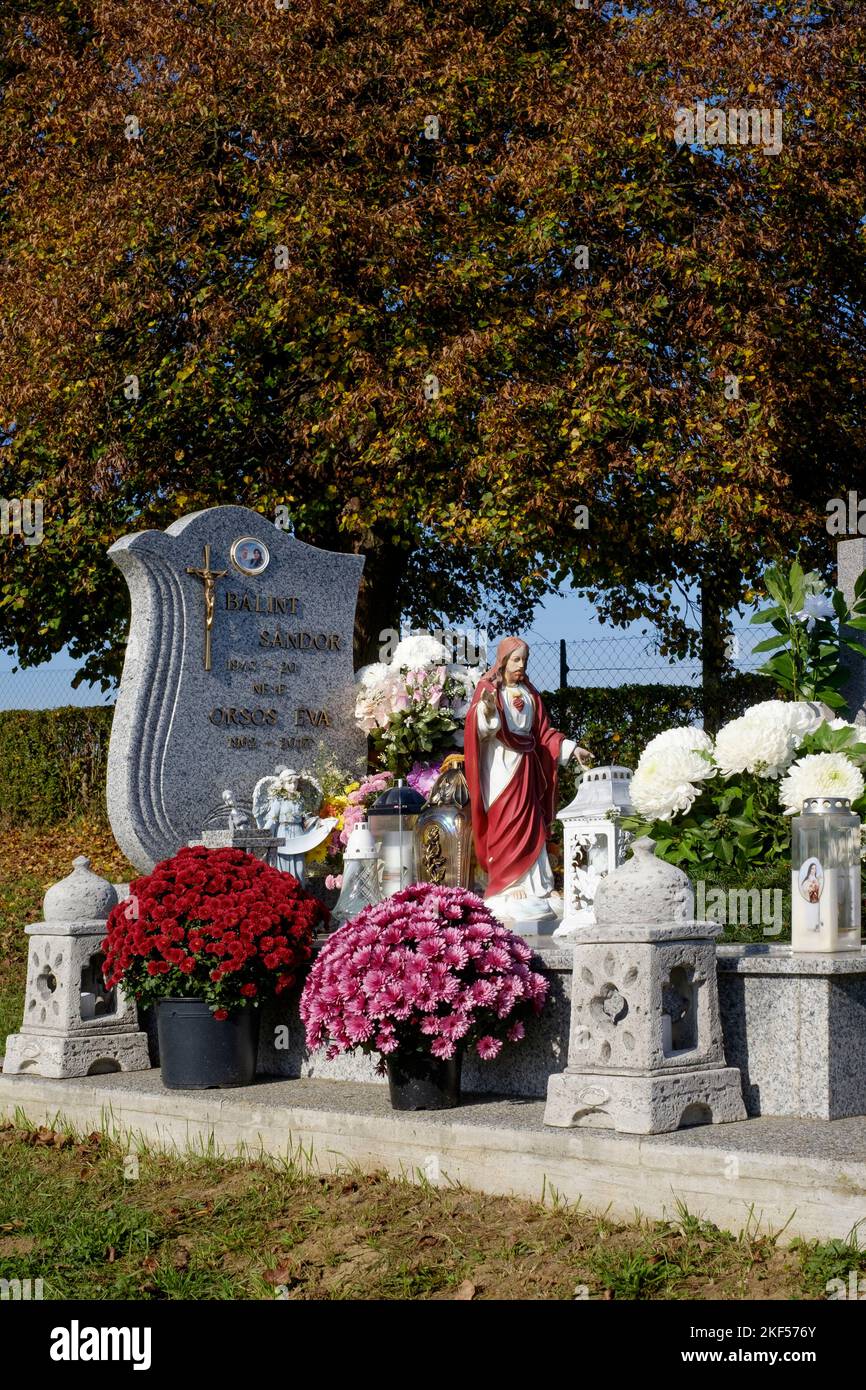 graves are decorated with fresh flowers candles lanterns at local rural cemetery for traditional all saints day zala county hungary Stock Photo