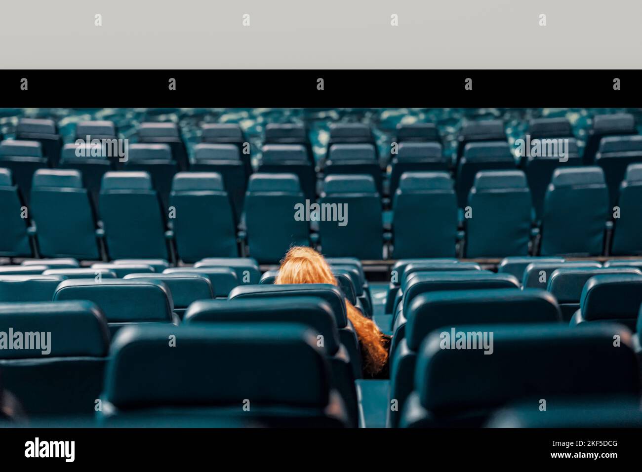 Abstract girl, lonely spectator in an empty cinema hall, empty seats Stock Photo