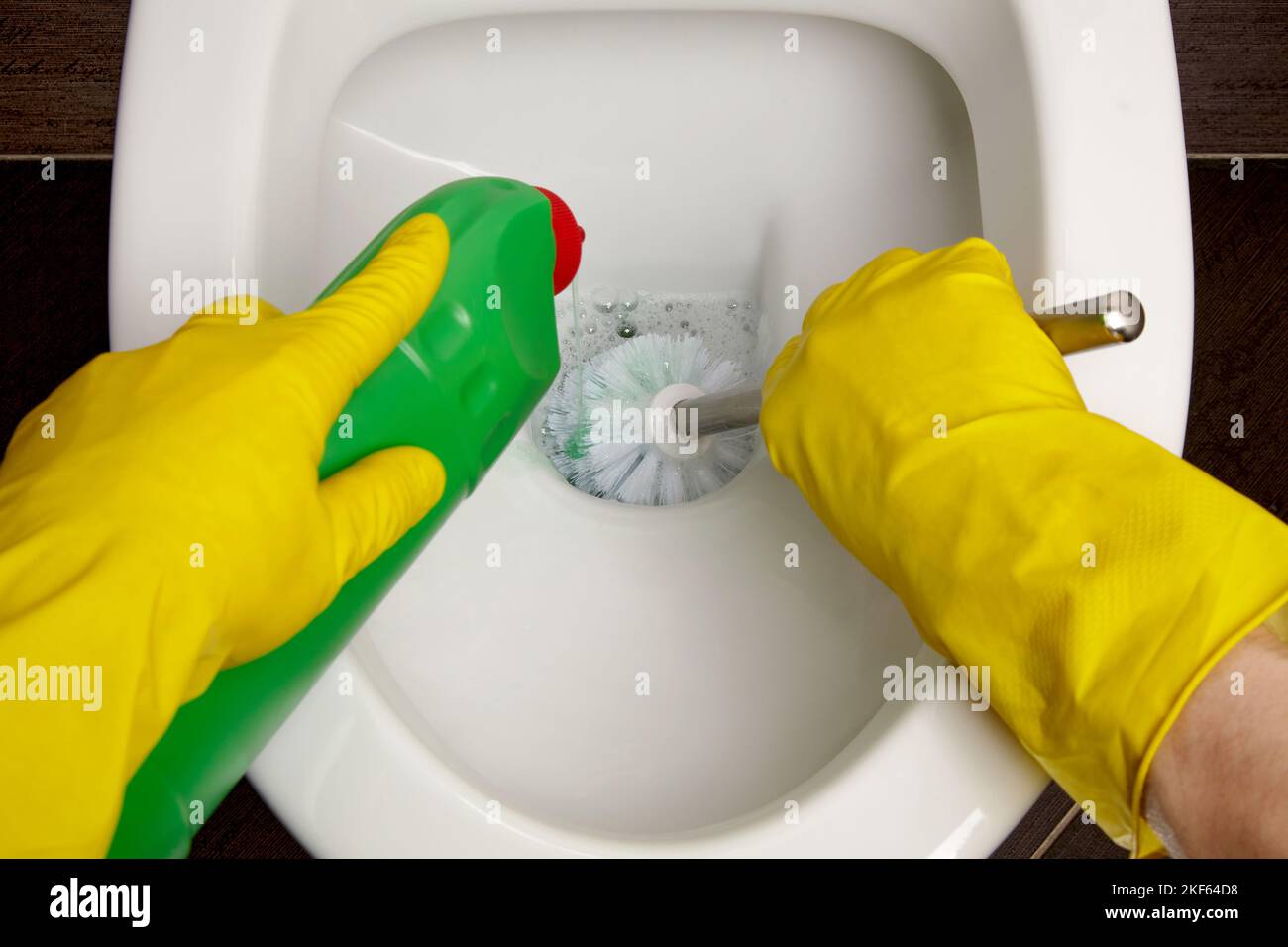 Toilet cleaning and disinfection. Cleaner in yellow rubber gloves