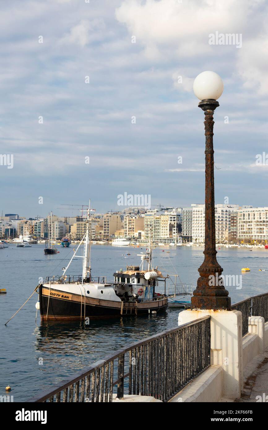 Sliema, Malta - November 12, 2022: Waterfront promenade with moored boats on cloudy morning Stock Photo