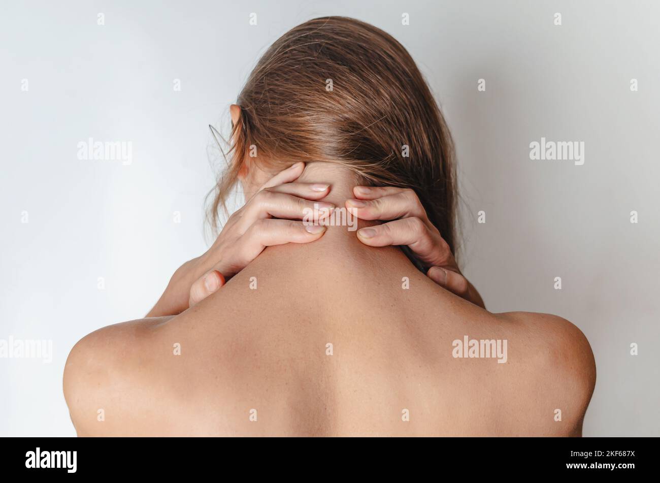 Close up woman with bare shoulders, hands behind her head. Rear view. SPA treatment. Stock Photo