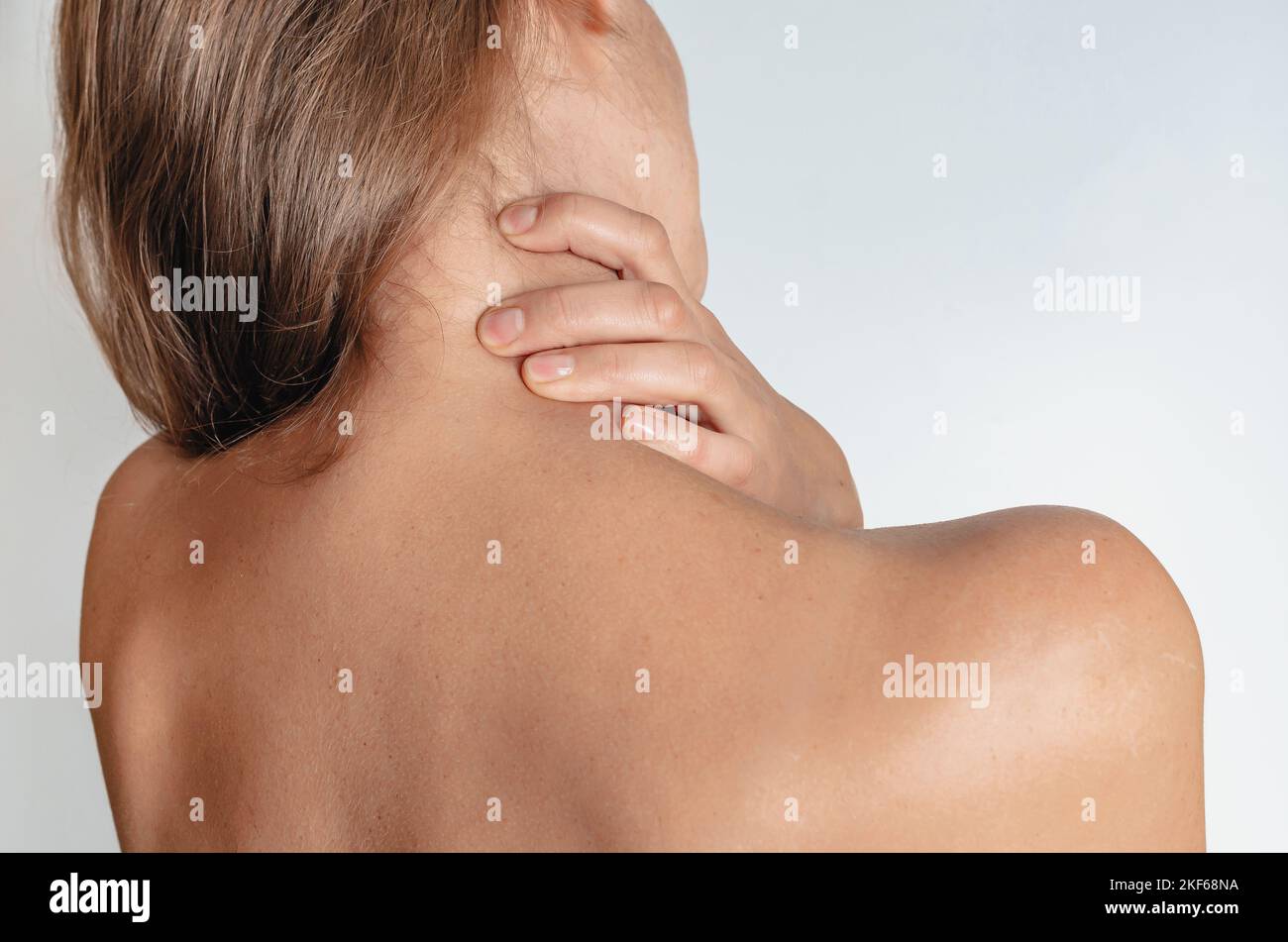 Massage for neck pain - woman with neck pain from behind, naked body Stock Photo