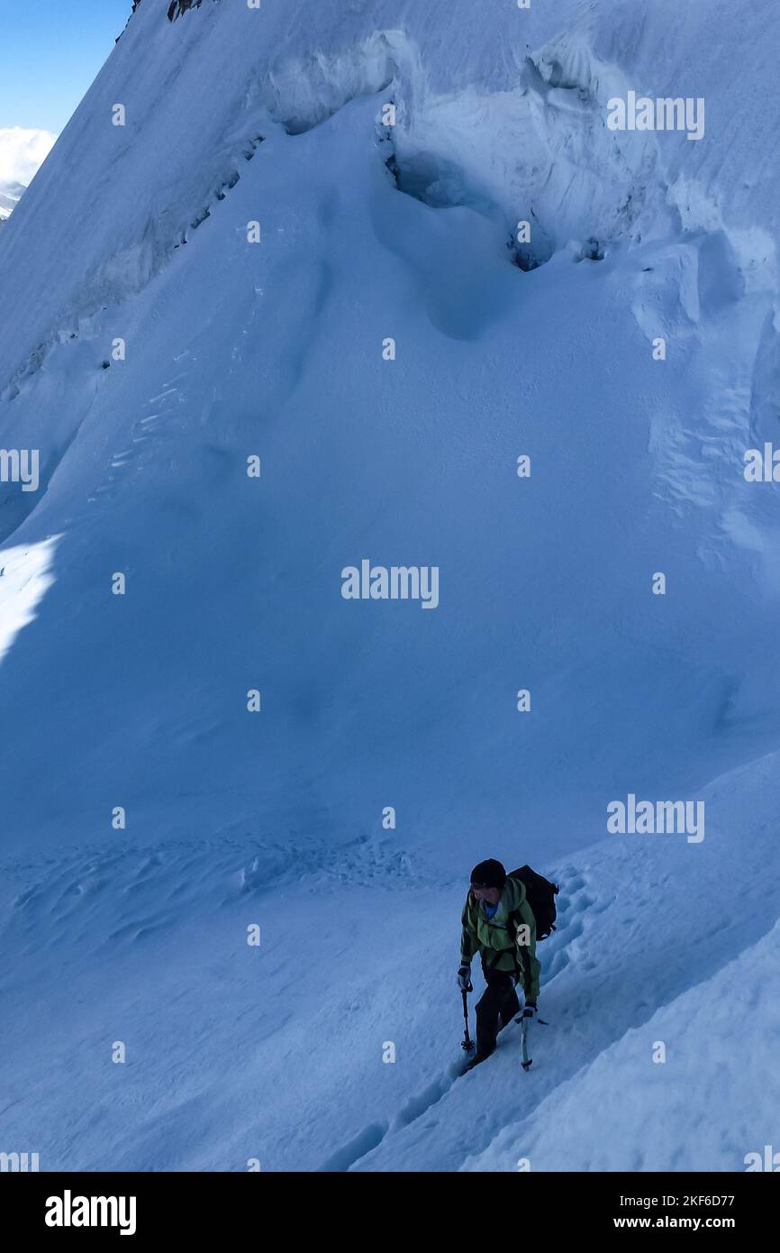Description Mountaineer climbing with ice axes over a steep snow slope