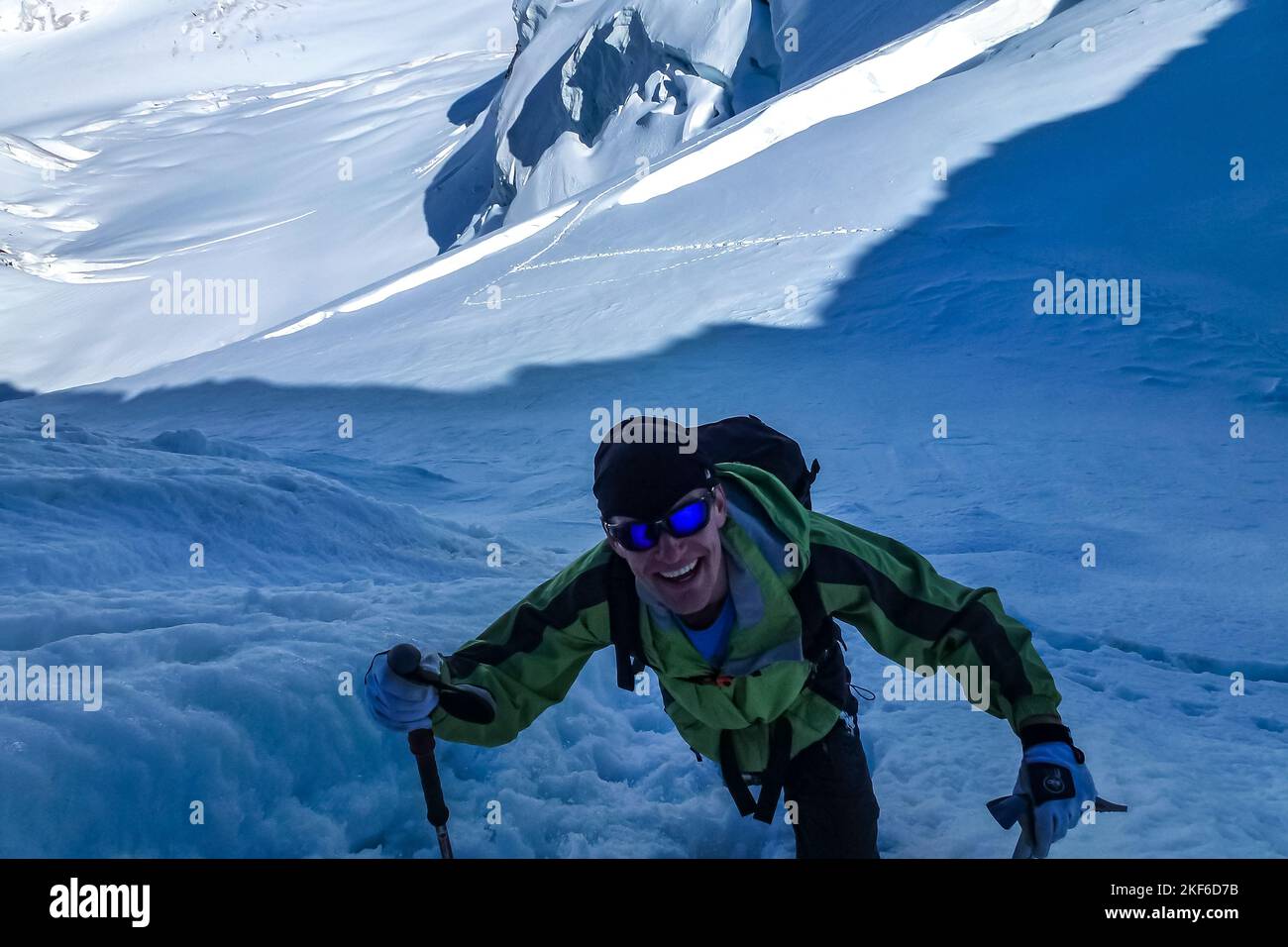 Description Enthusiastic mountaineer climbing with ice axes over a