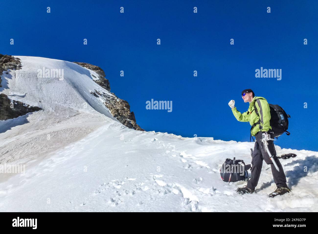 Description: Enthusiastic mountaineer with ice axe enjoys panorama ...