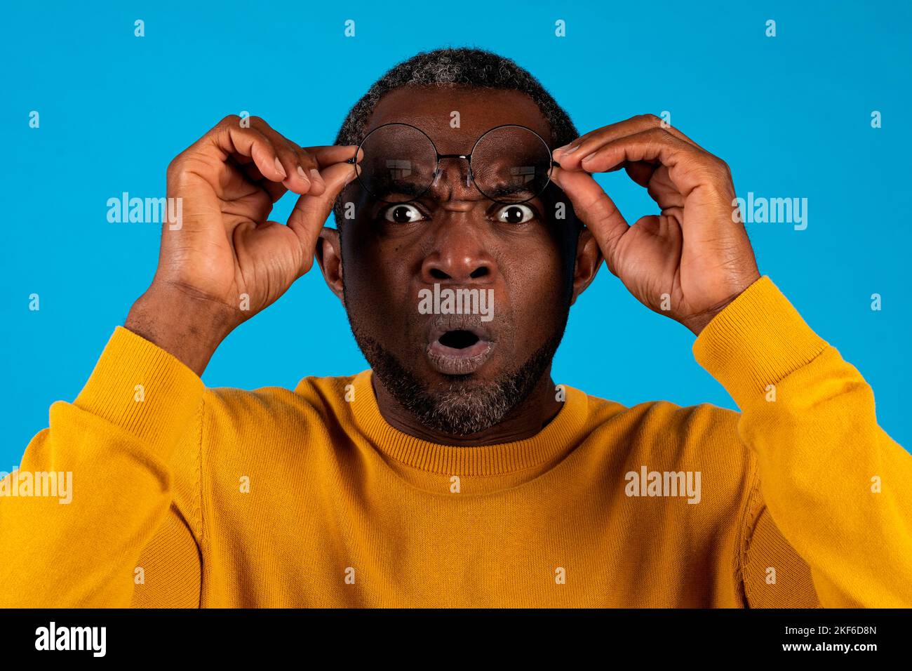 Shocked mature african american man removing eyeglasses on blue Stock ...
