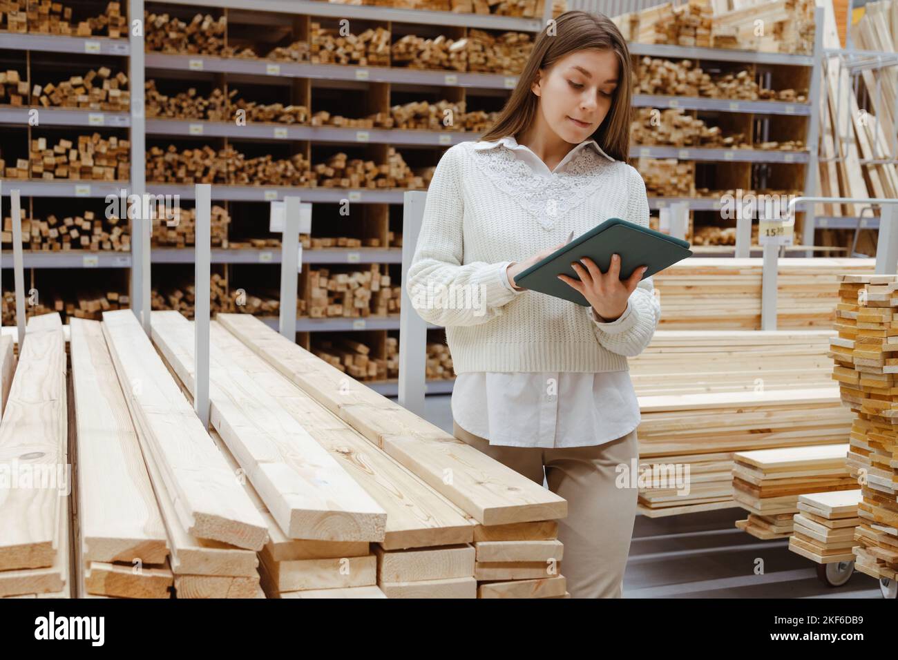 Woman with tablet in a timber and lumber warehouse or hardware store