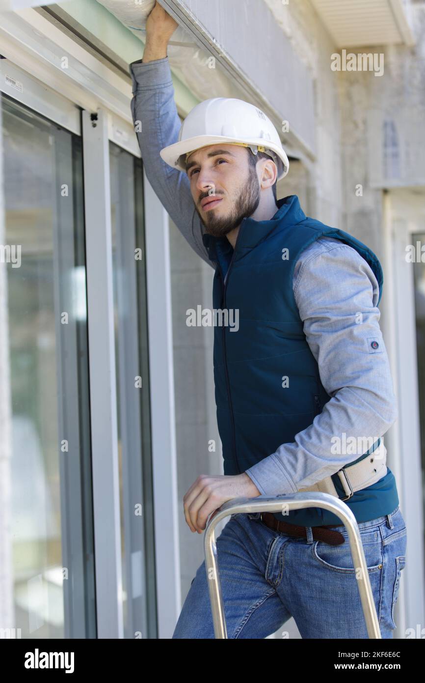 builder working on roller shutter above patio doors Stock Photo Alamy