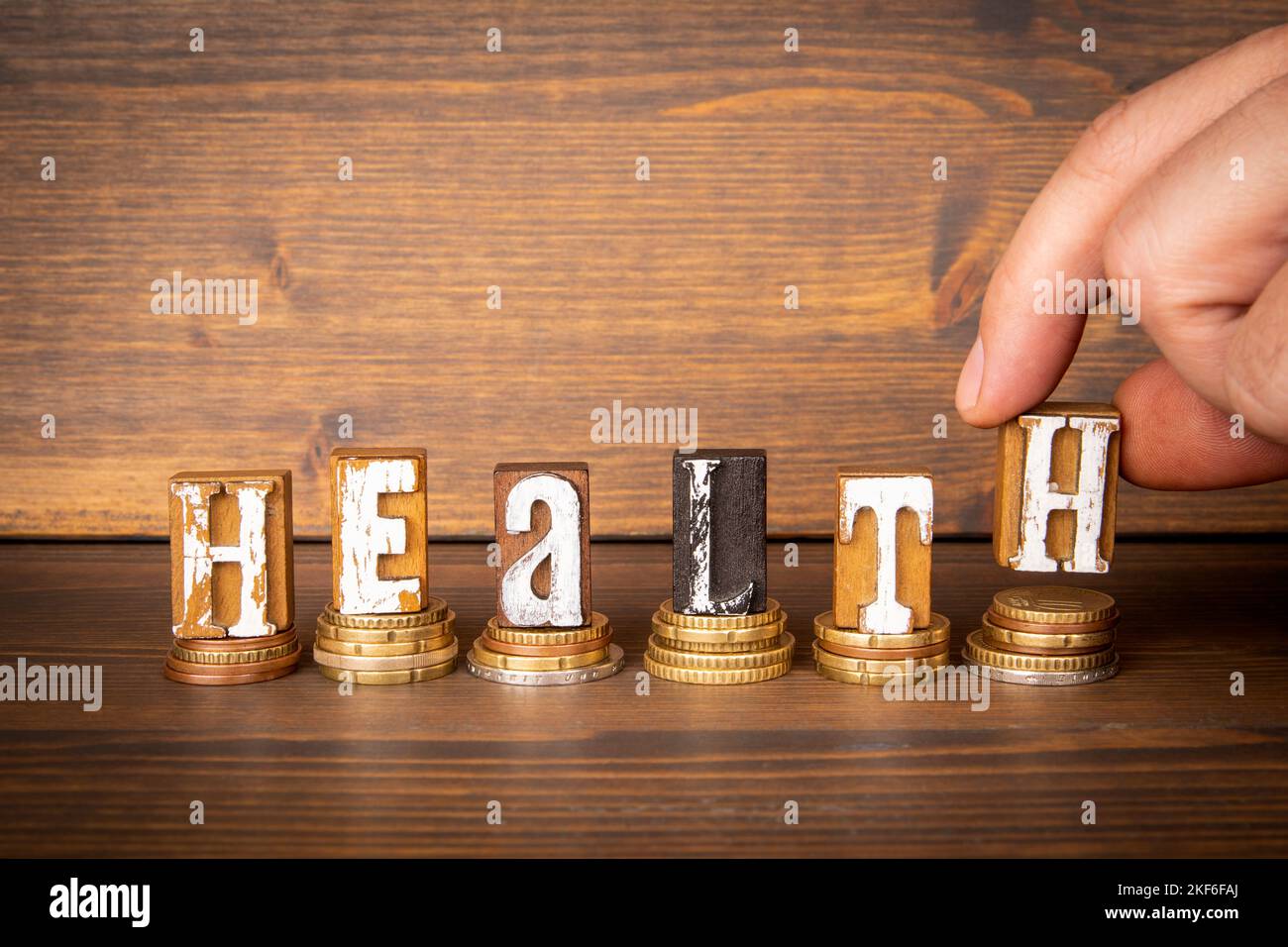 Health. Coins and alphabet blocks on a dark wooden background. Stock Photo