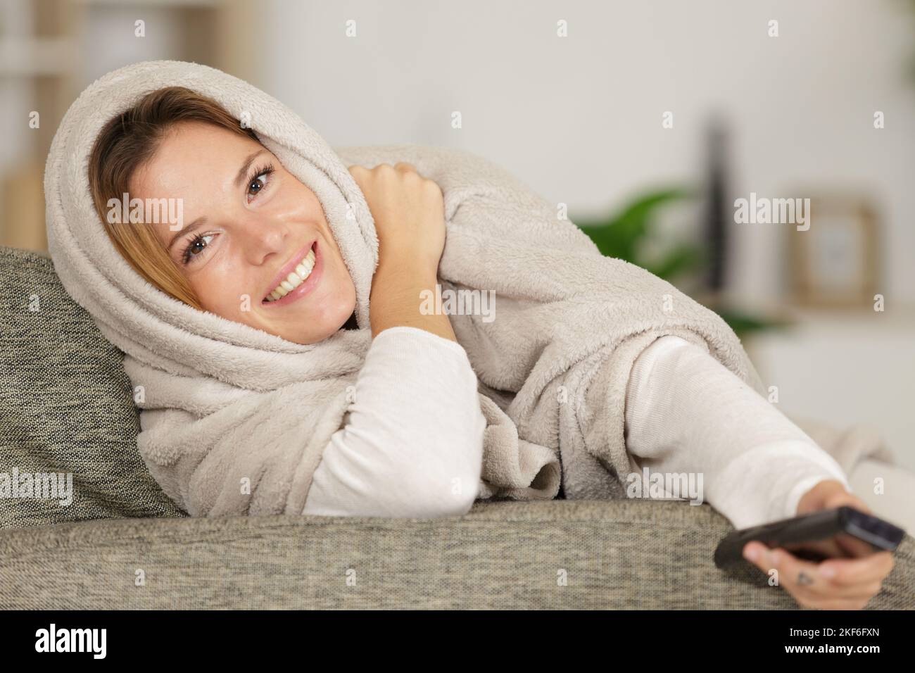 young woman covered with blanket watching tv Stock Photo Alamy