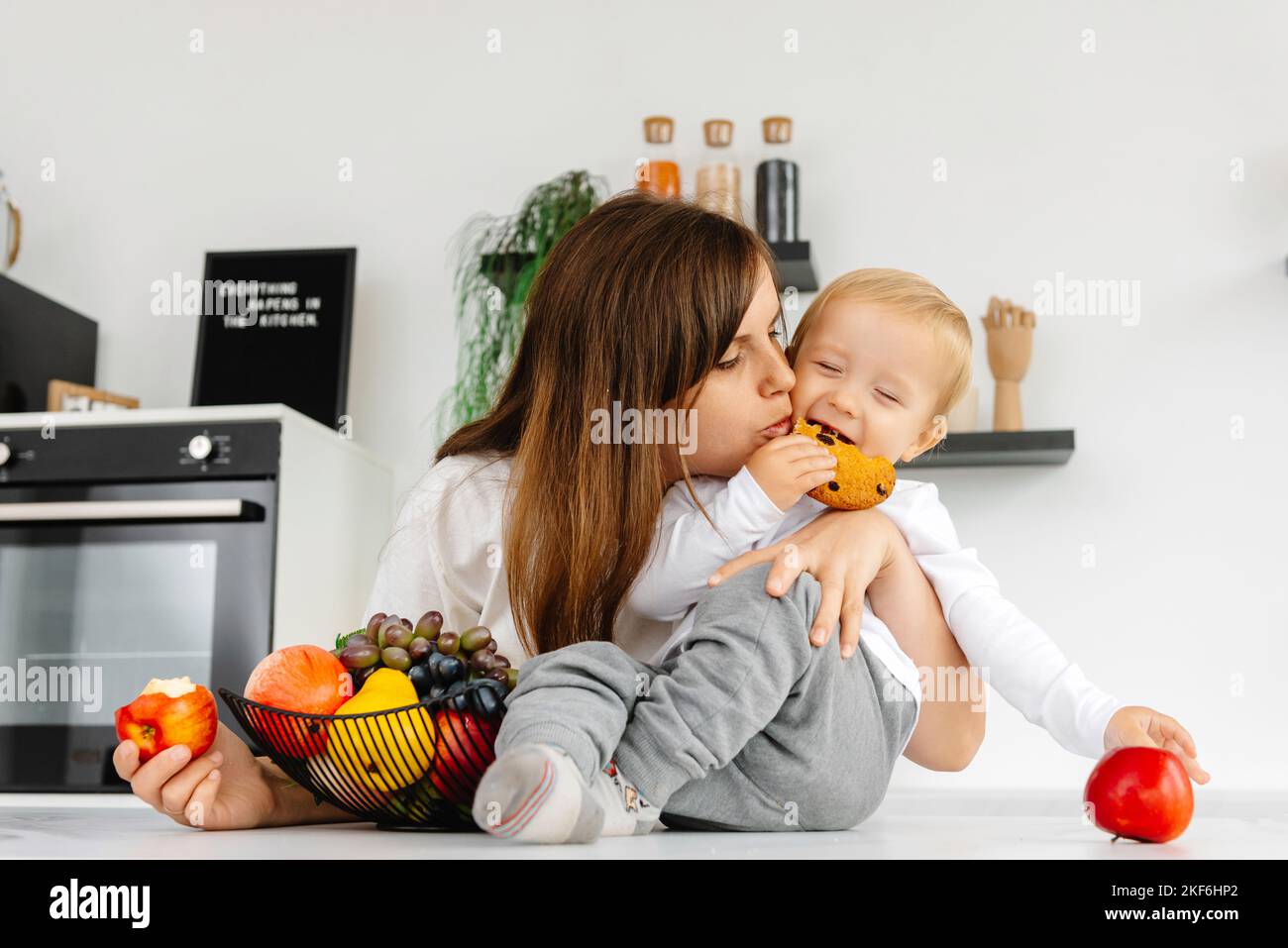 Happy Family Mom hugging baby and eating apples and healthy food ...
