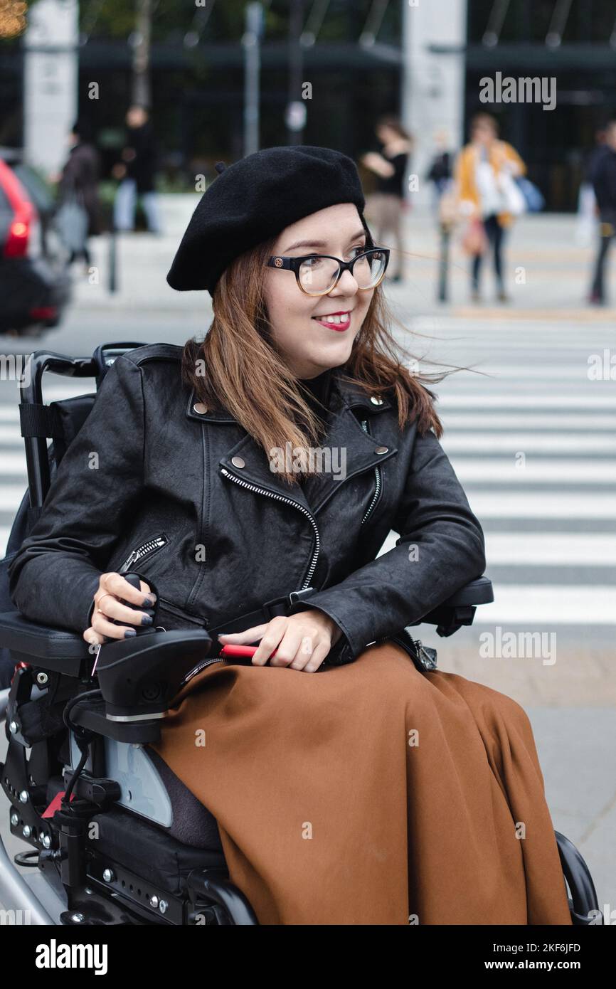 Brunette woman sitting in wheelchair on city street Stock Photo