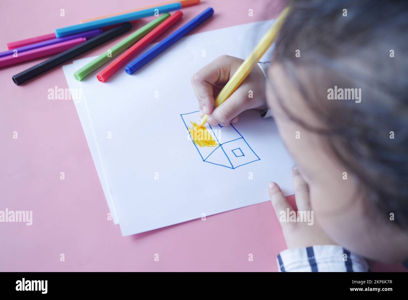 Close up of a child hand drawing with colored pencil on a page. Stock Photo