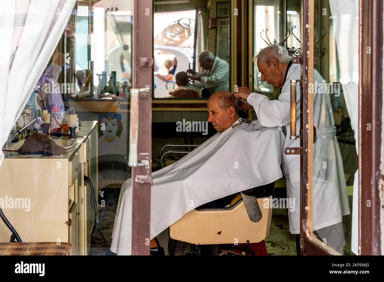 An Elderly Barber Cutting Hair, Ortigia, Syracuse (Siracusa), Sicily, Italy Stock Photo