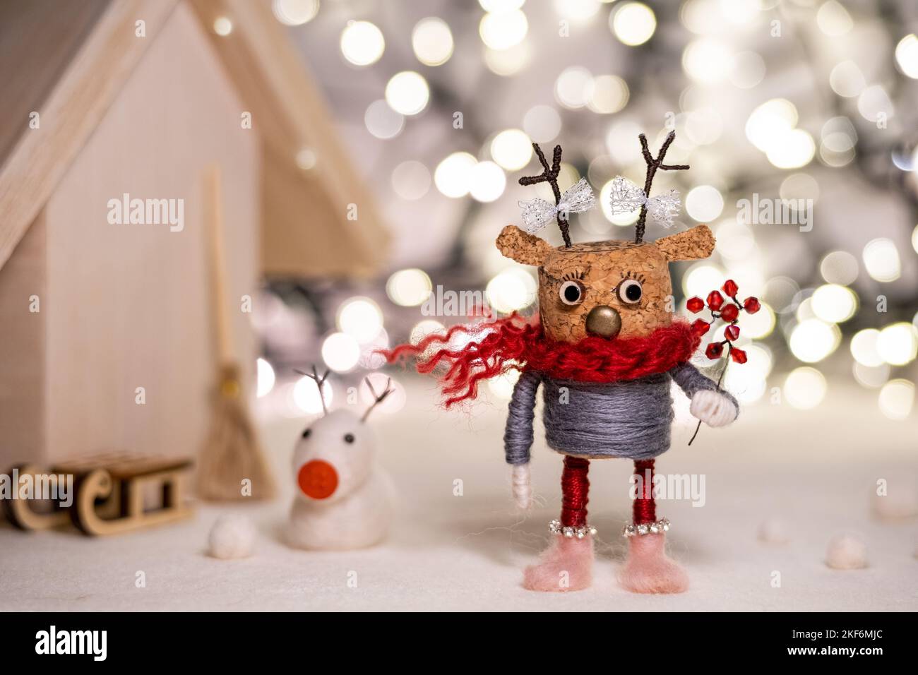 A cozy scene featuring Merry Christmas in fluffy, white script, nestled  in a bed of cute, cartoon-like woolen mittens and scarves, with a softly  blurred snowfall background