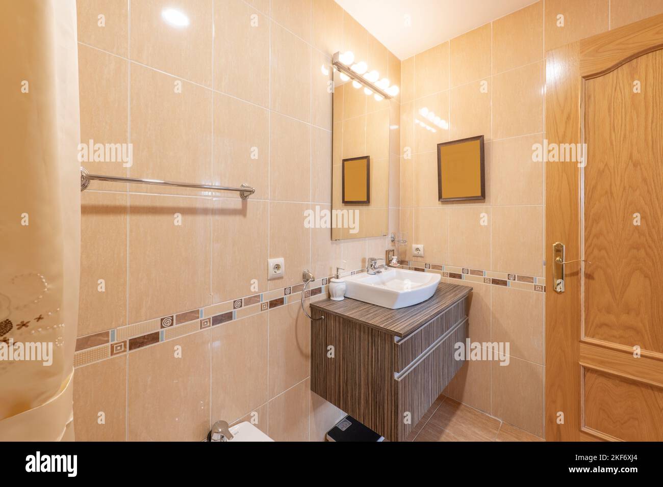 Bathroom with wooden wall cabinet with a frameless mirror above it Stock Photo