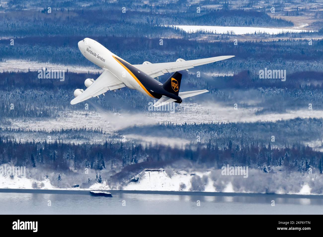UPS Cargo Boeing 747-8F aircraft banking after take off. Airplane of UPS Cargo 747 freighter departure with winter landscape below. Plane N607UP. Stock Photo
