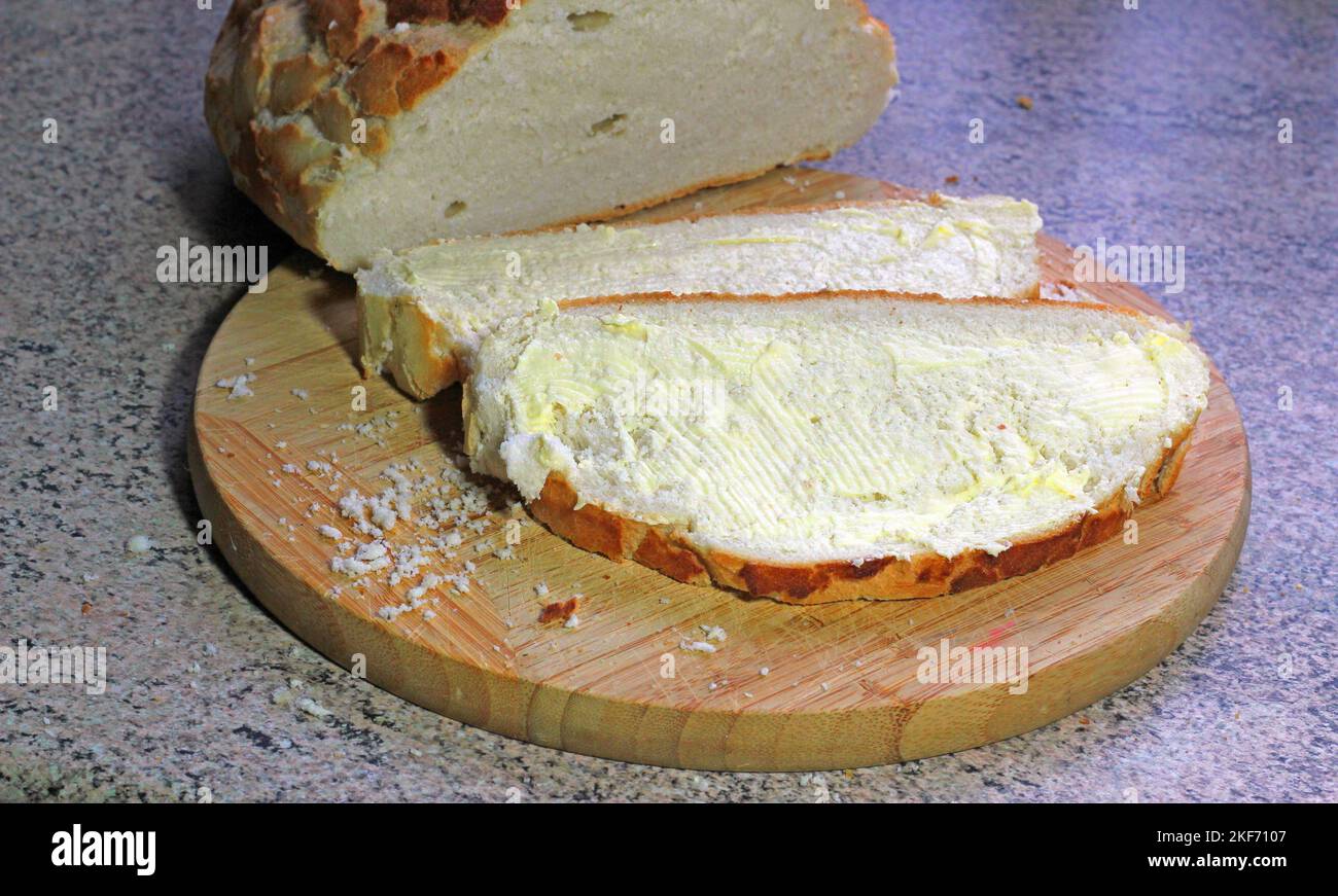 Freshly cut bread on a bread board. Two white slices. Stock Photo