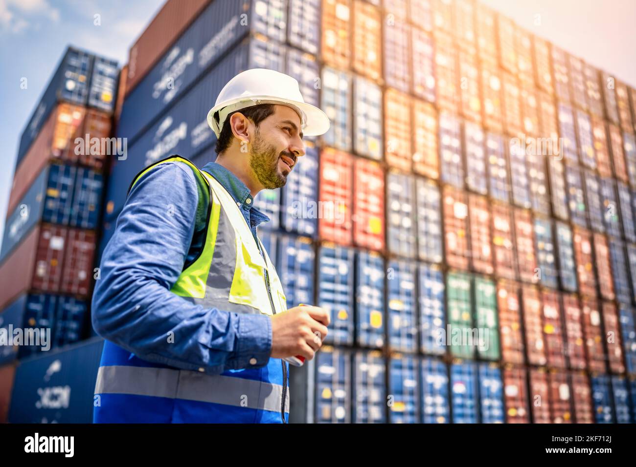 Handsome Engineer or foreman wears PPE checking container storage with cargo container background at sunset. Logistics global import or export shippin Stock Photo