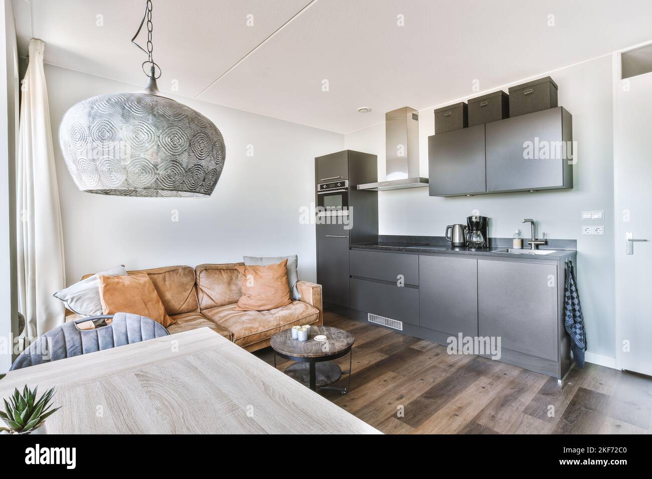 Contemporary open plan kitchen with dining table set and gray sofa in ...