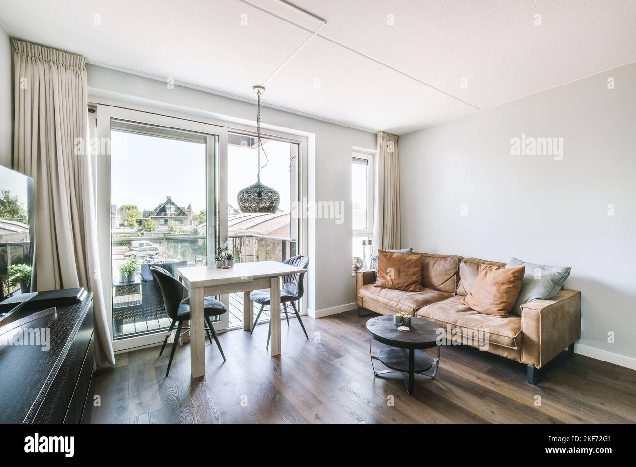 Contemporary open plan kitchen with dining table set and gray sofa in
