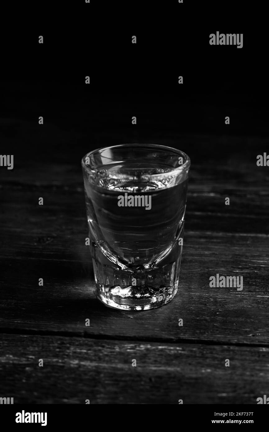 Ukrainian gorilka or vodka or tequila (transparent highly alcoholic drink) shot on dark background. Stock Photo
