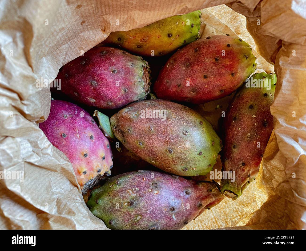 Prickly pear cactus colorful fresh ripe whole and cut fruits in brown paper bag. Stock Photo