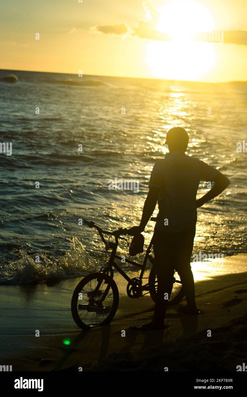 Beautiful yellow sunset at caleta de la romana beach dominican republic showing the silhouettes of plants and people Stock Photo