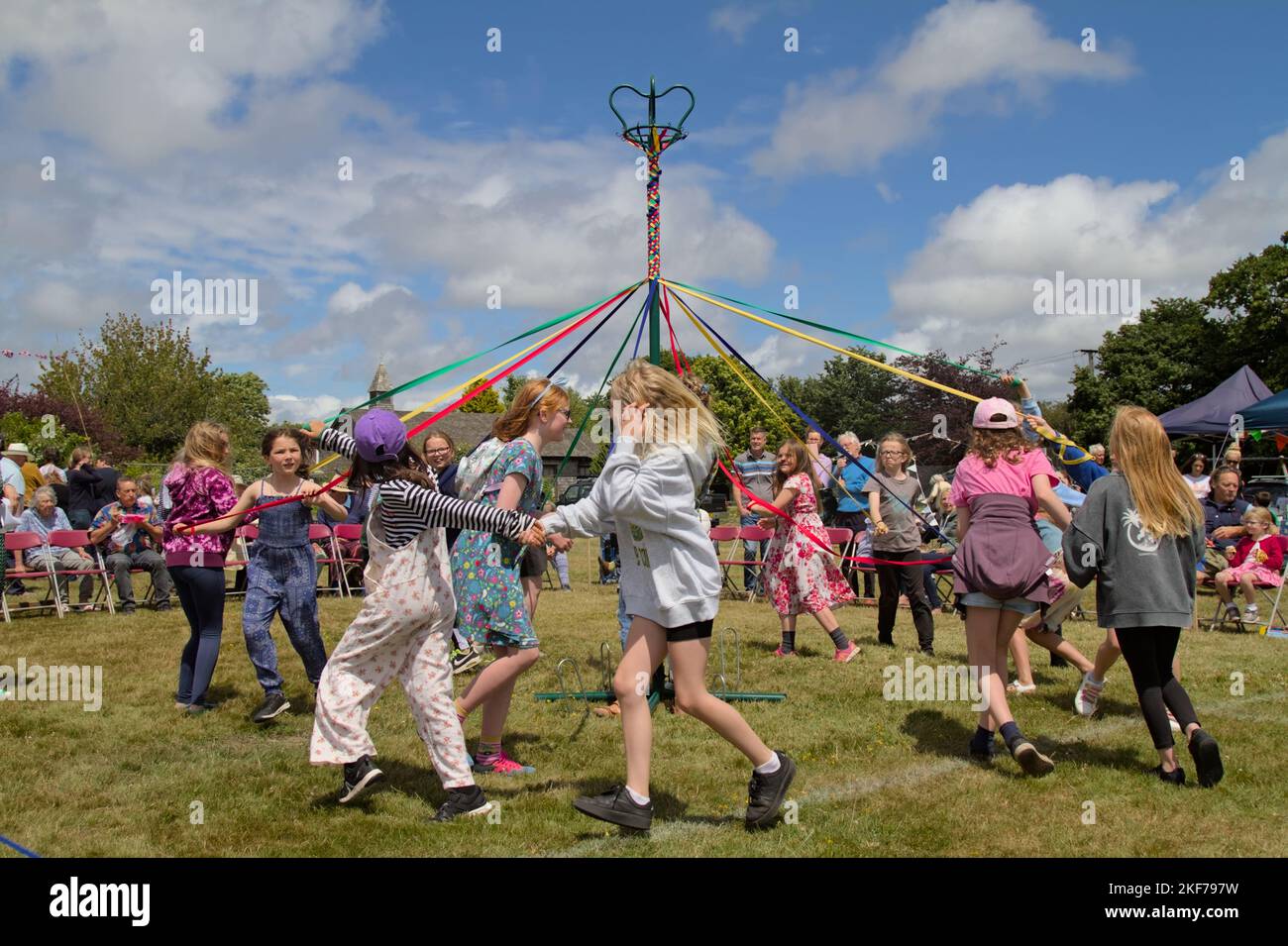 Children Holding Ribbons Dancing Round A Maypole On A Summers Day At