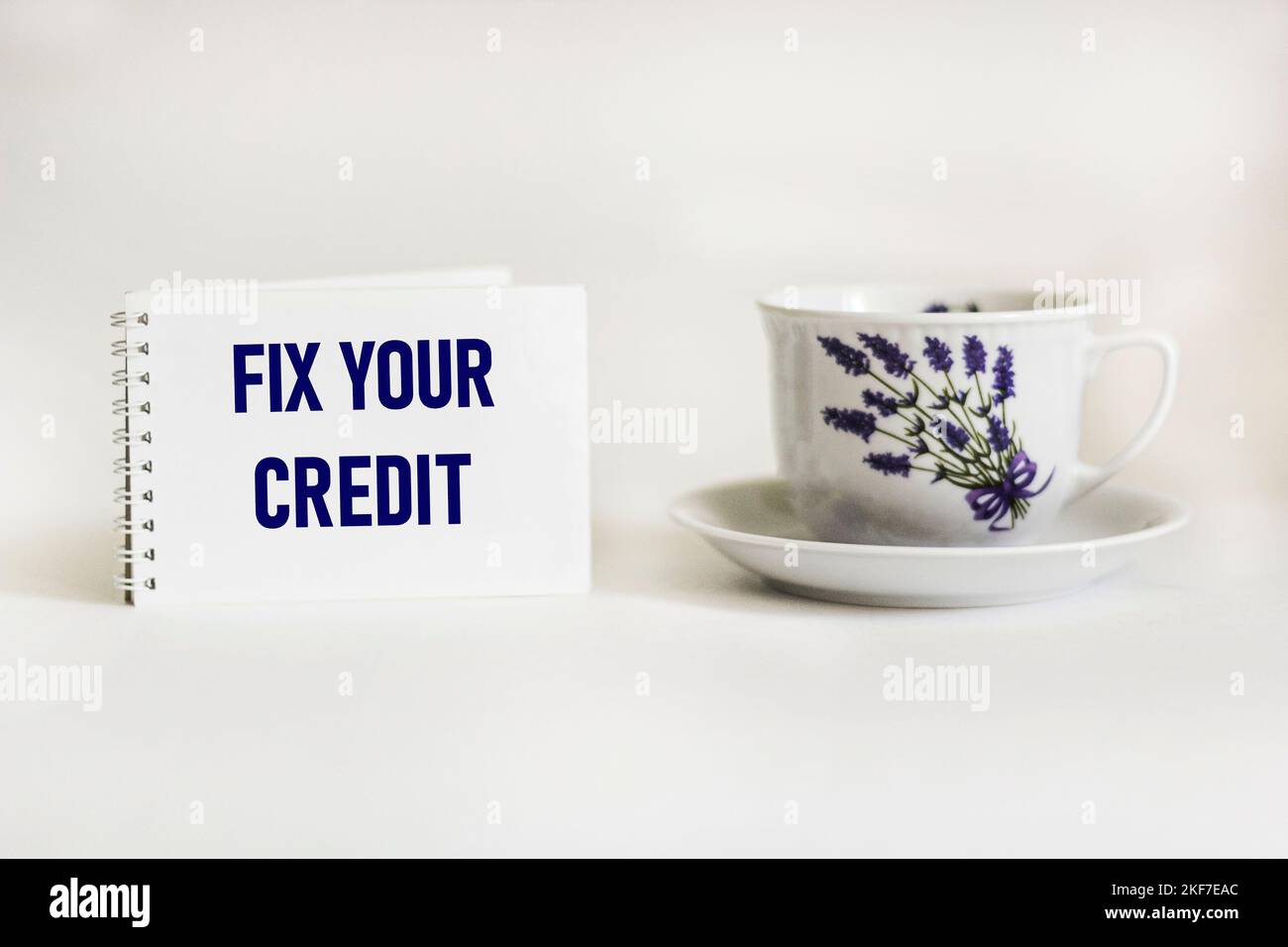 Fix Your Credit text written on notepad and white background with beautiful tea cup .Conceptual photo. Evaluation tips fix improvement Stock Photo