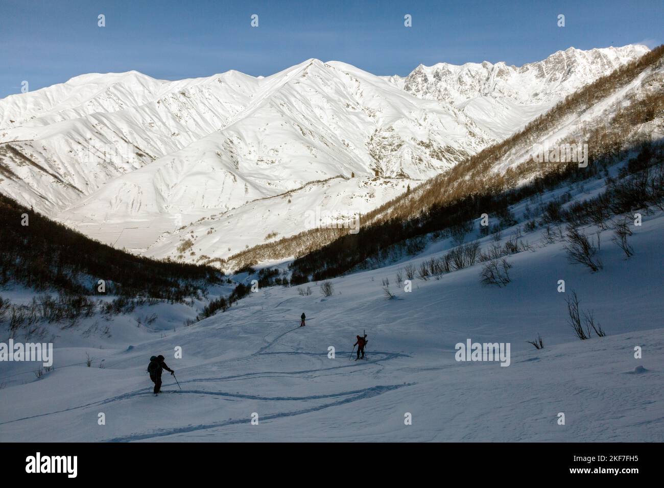 A team of freerider skiers climbs against the background of snowy ridges of the Caucasus Mountains, Svaneti, Georgia, backcountry Stock Photo