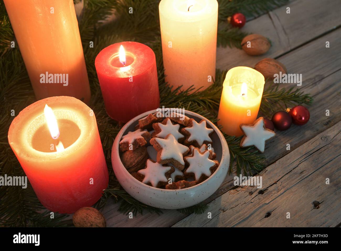 Cinnamon star cookies between glowing candles and fir tree branches, decoration in Advent and Christmas time, copy space, selected focus, narrow depth Stock Photo