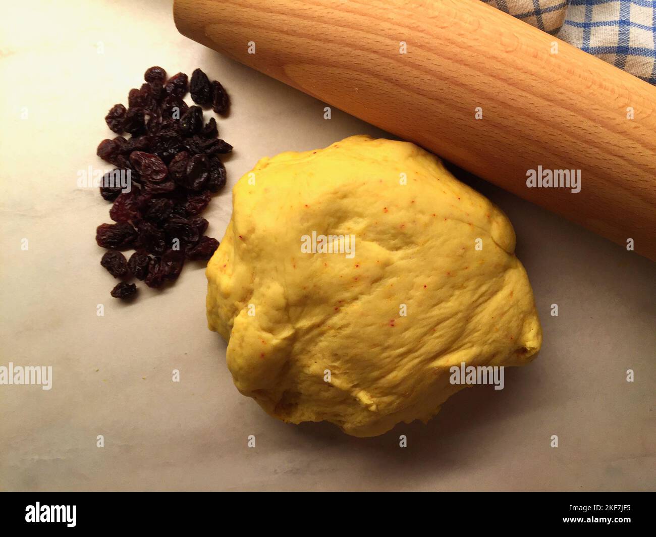 Saffron dough and raisins on a baking table for baking buns for December holidays. Stock Photo