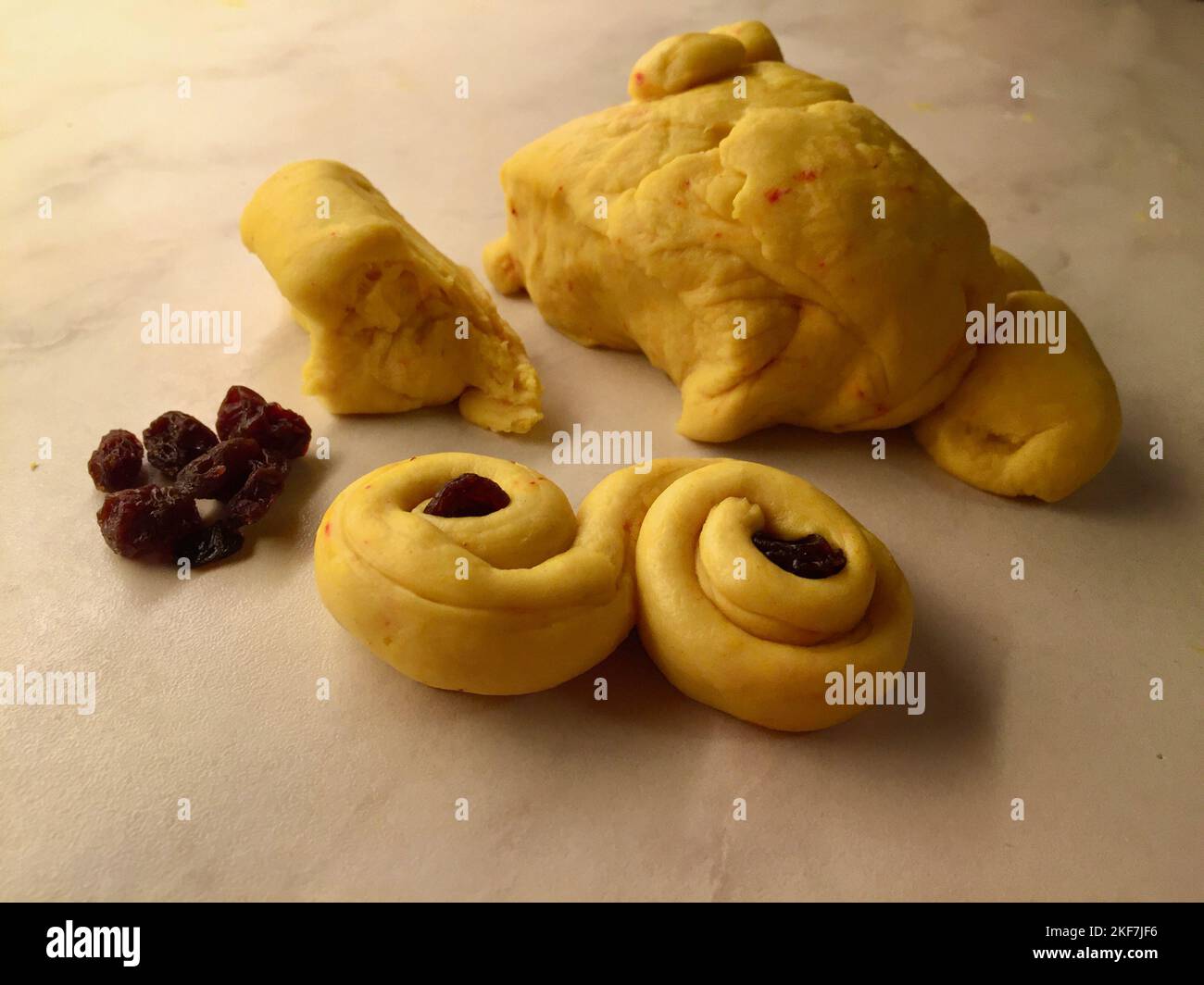 Saffron dough and raisins on a baking table for baking buns for December holidays. Stock Photo