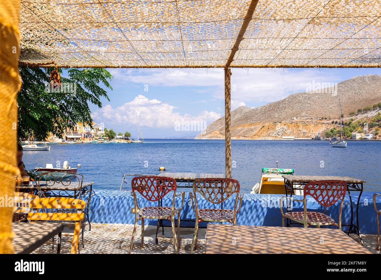 Panoramic view of small haven of Symi island. Village with Street Cafe and colorful houses located on rock.  Stock Photo