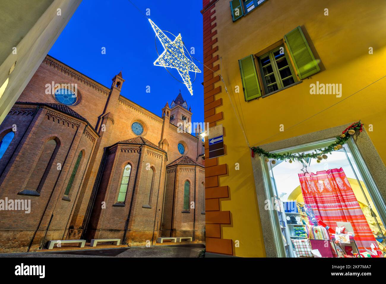 San Lorenzo cathedral, building with windows and wooden shutters and star shaped Christmas decoration illuminated in the evening in Alba, Italy. Stock Photo