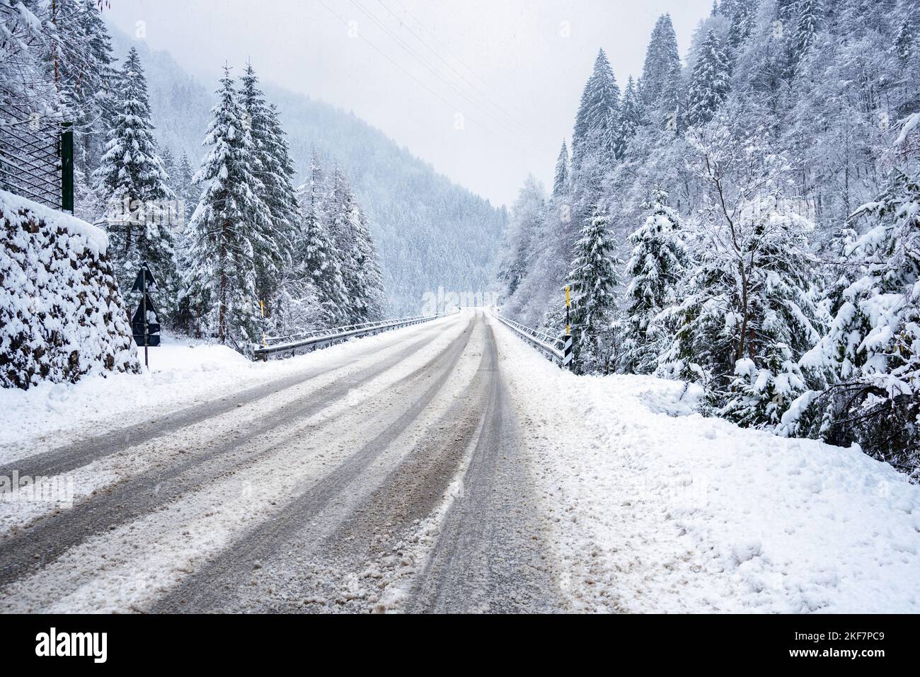 Deserted road covered in fresh snow in the mountains during a blizzard Stock Photo