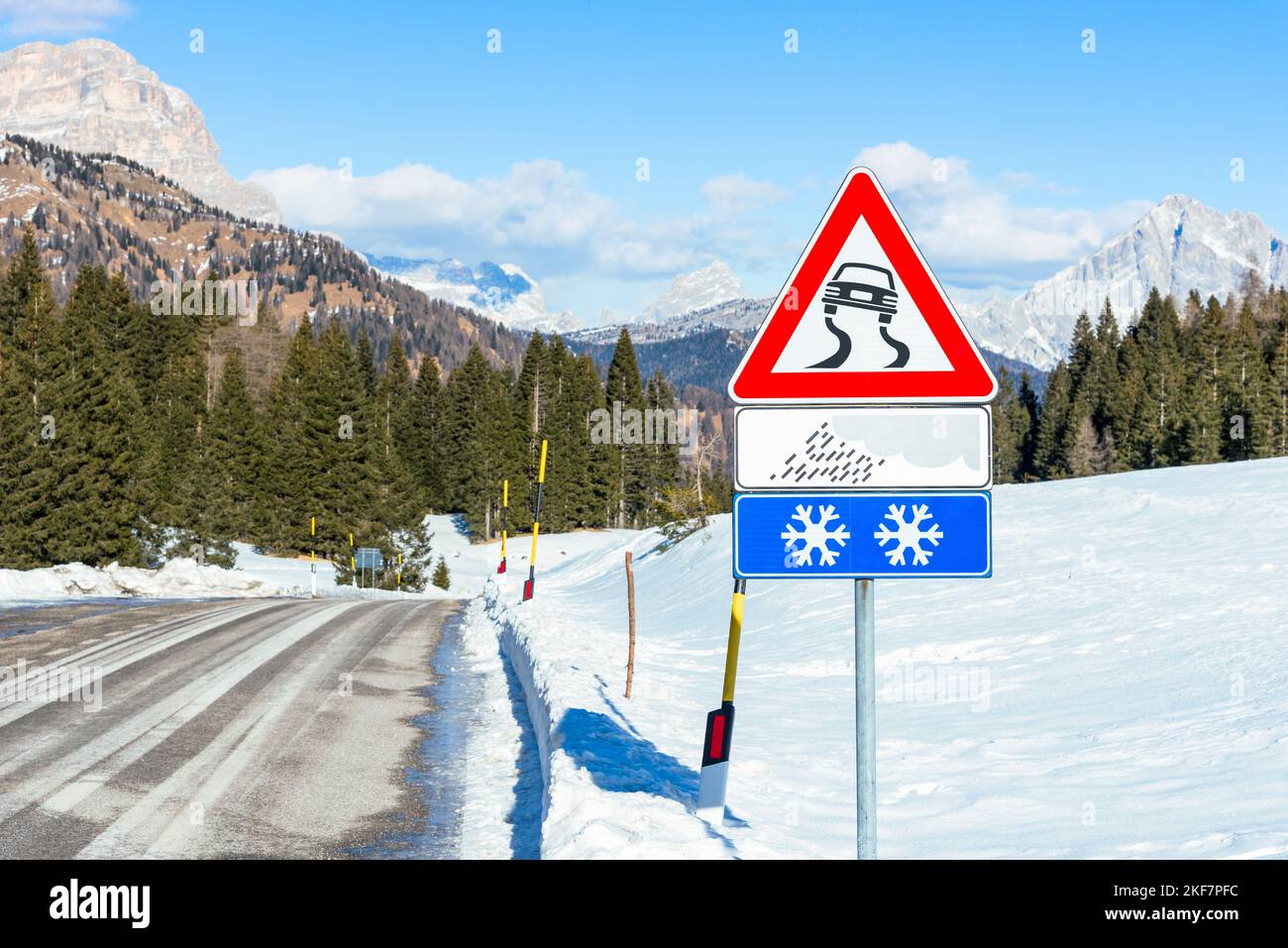 Slippery road  warning sign along a mountain road on a sunny winter day Stock Photo