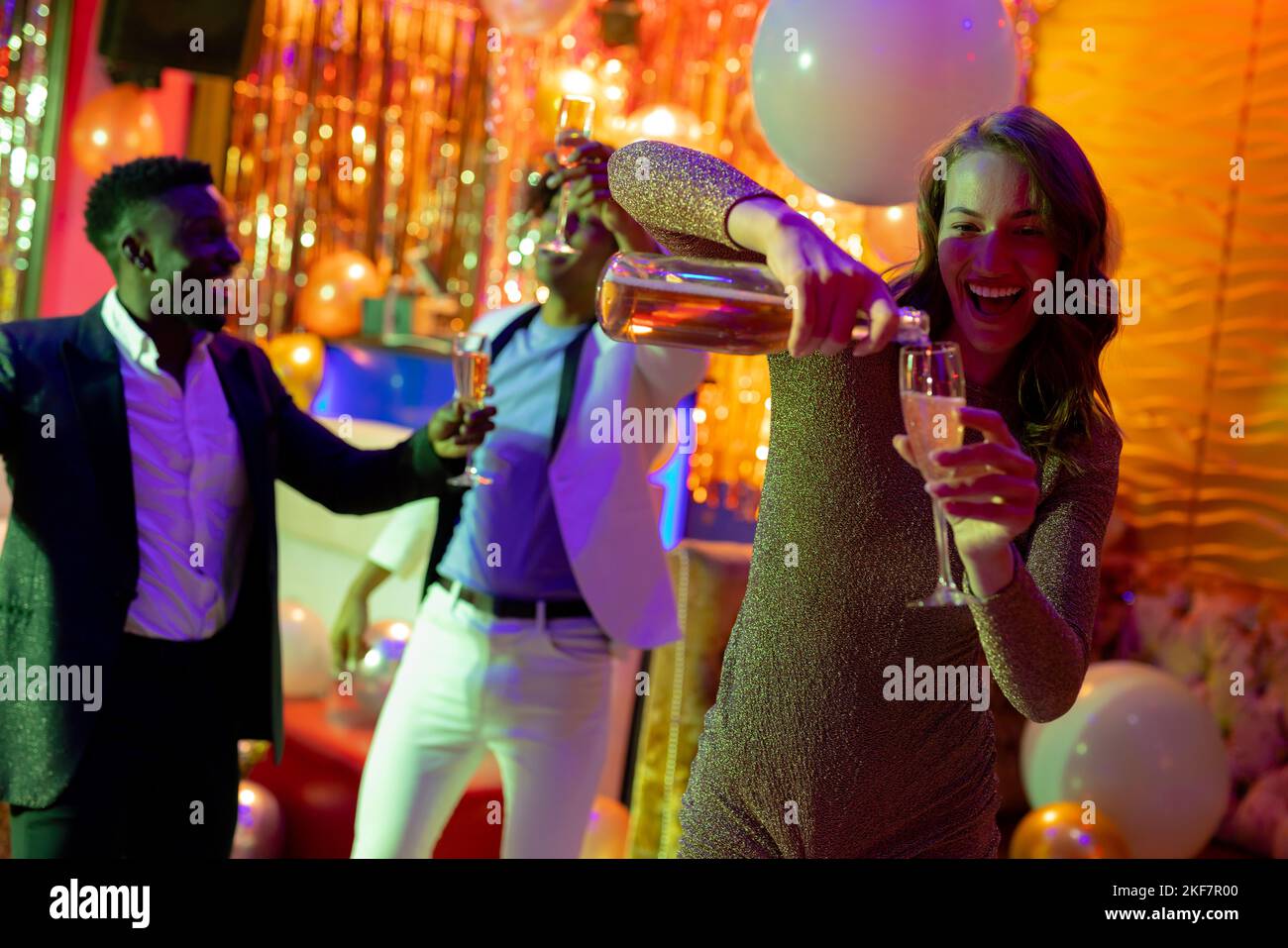 Smiling caucasian woman pouring glass of champagne at nightclub. Fun, drinking, going out, inclusivity and party concept. Stock Photo