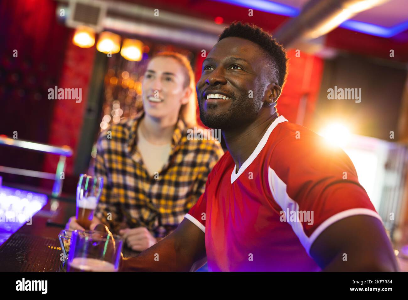 Diverse, excited male and female friend watching sports game showing at a bar Stock Photo