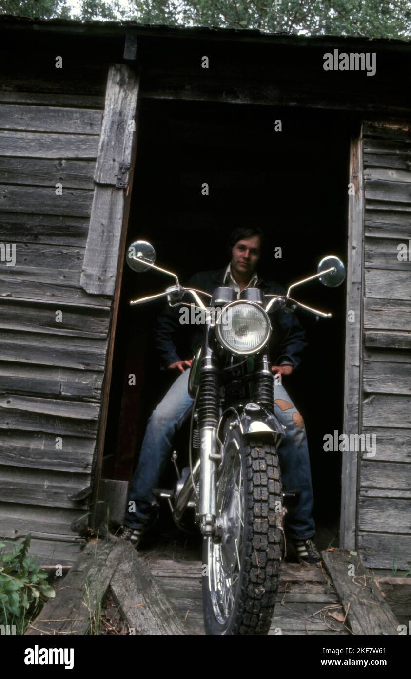 Vintage or retro photo of a motorcyclist (Triumph Bonneville) posing for a portrait. Circa 1975 Stock Photo