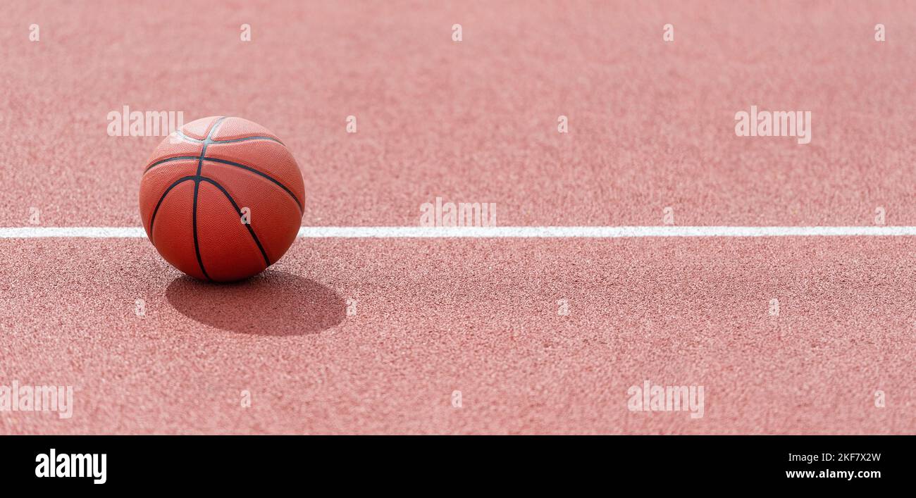 Orange basketball on brown court of gymnasium sport floor. Street