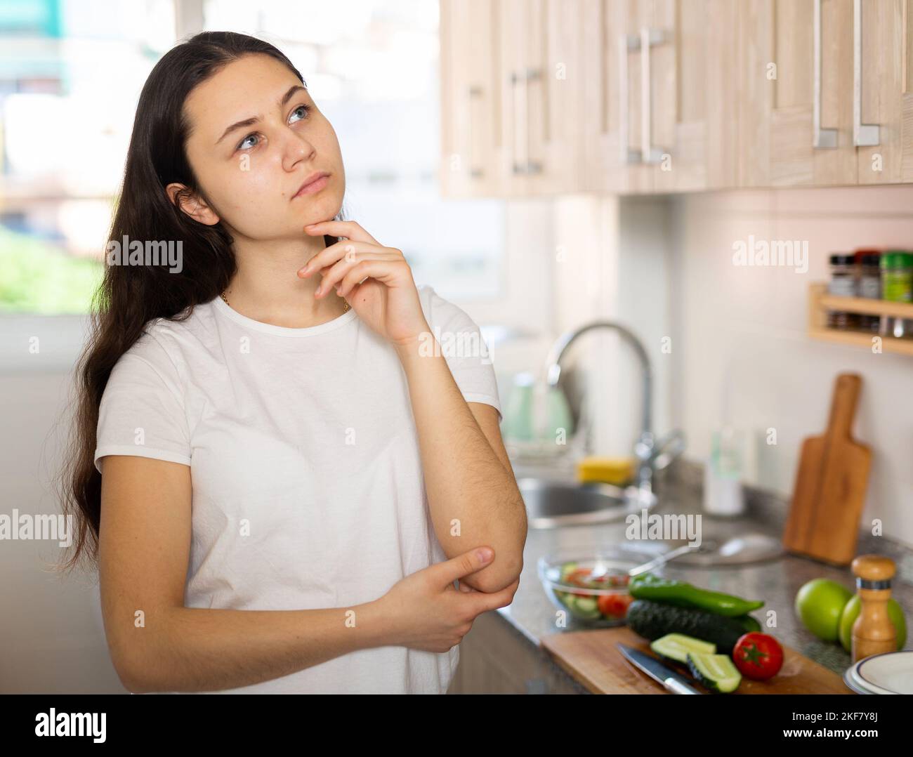 Portrait of confused young woman at kitchen Stock Photo - Alamy